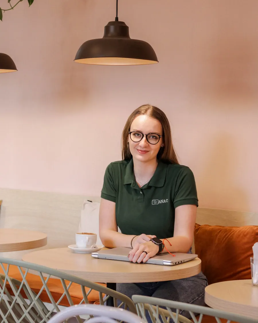 Ana sentada à mesa de um café, com o notebook fechado e uma xícara ao lado