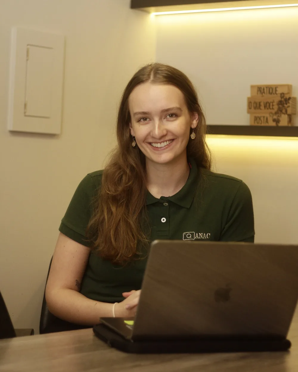 Ana Carolina Rohsig, à frente da ANAC Comunicações, sorrindo em frente ao notebook